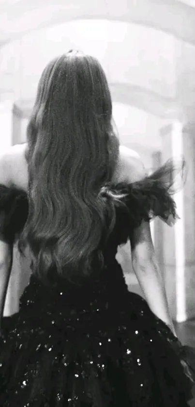 Back view of a woman in an elegant black dress with flowing hair.