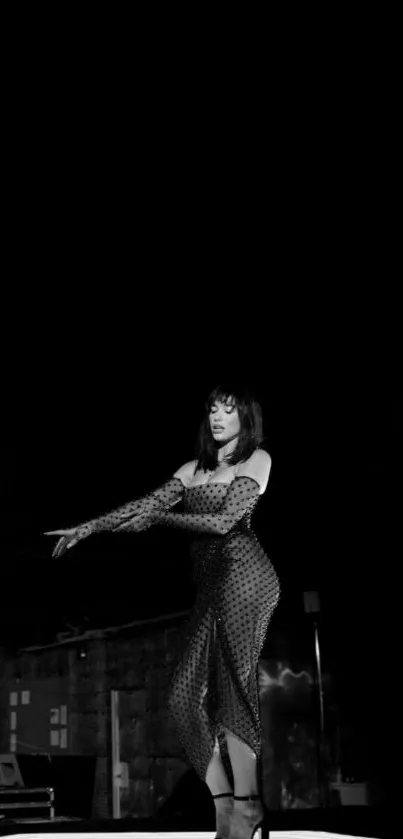 Woman in elegant black polka-dot dress on stage, monochrome aesthetic.