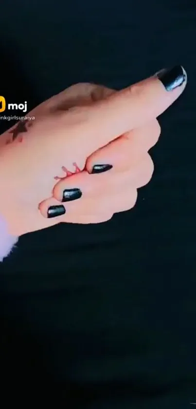 Hand with black nail art on dark background wallpaper.