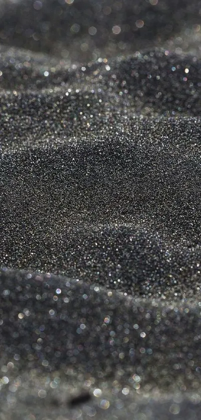 Close-up of textured black sand with subtle waves.