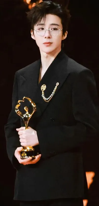 Person in black suit holding a golden award, ideal for phone wallpaper.