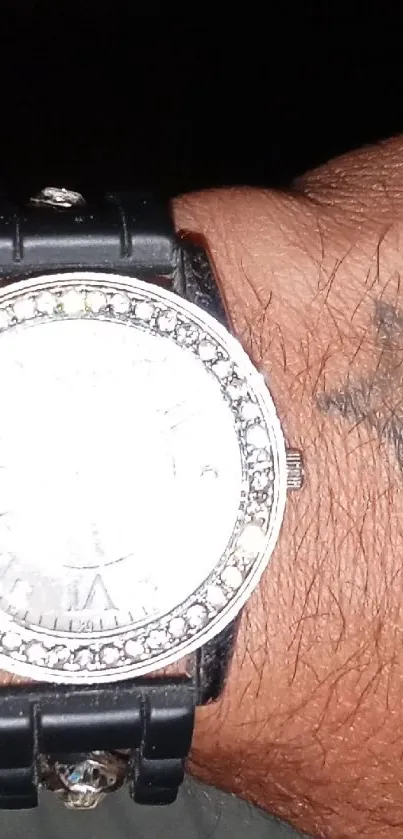 Close-up of a black watch on tattooed wrist.