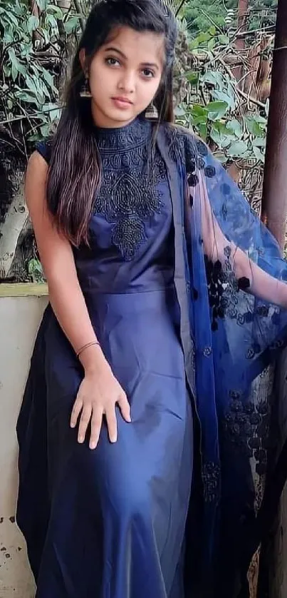 Woman in an elegant navy blue dress sitting outdoors.