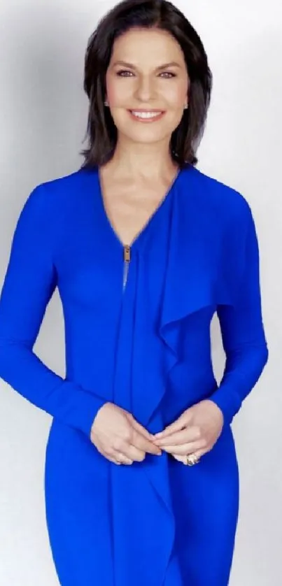 Woman in a cobalt blue dress posing elegantly against a neutral background.