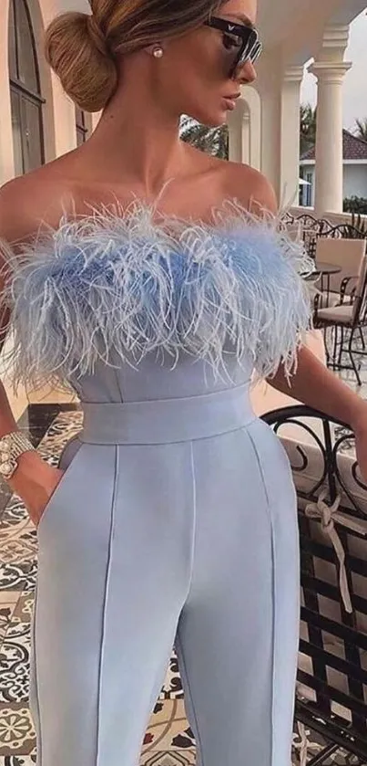 Woman in a light blue feathered outfit posing elegantly outdoors.