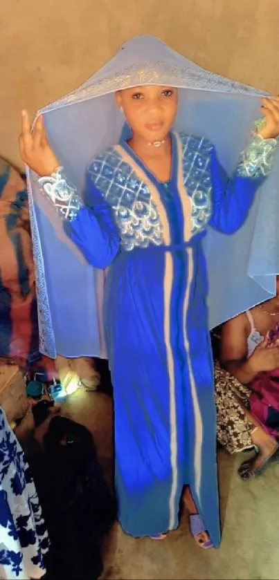 A woman in a blue hijab poses elegantly indoors.
