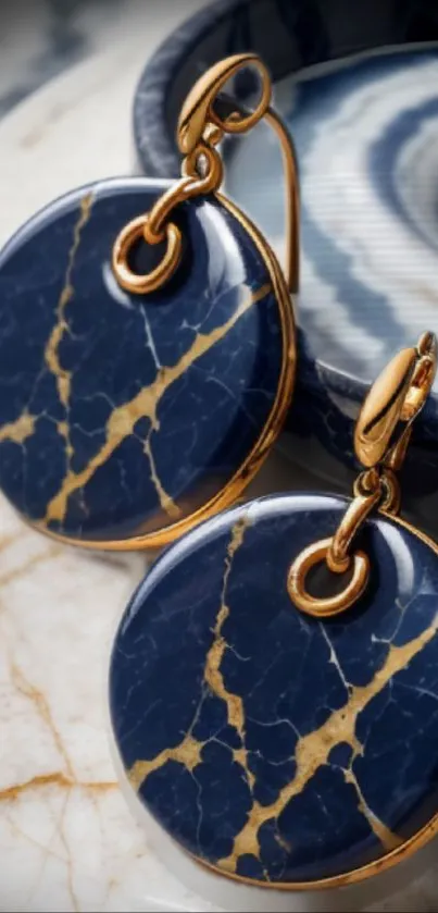 Close-up of elegant blue marble earrings with gold accents on textured background.