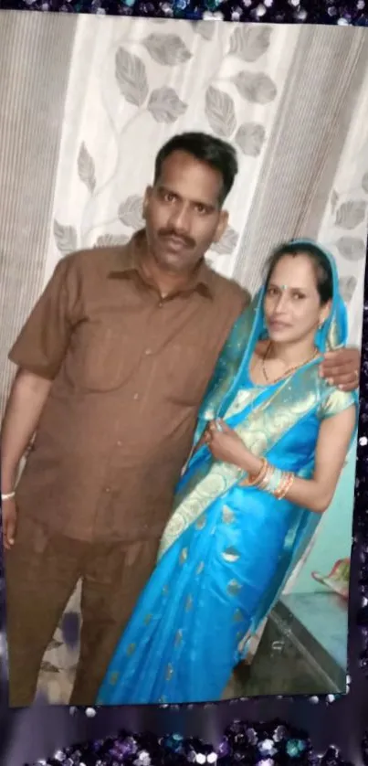 Couple in traditional attire with blue saree and sequin background.