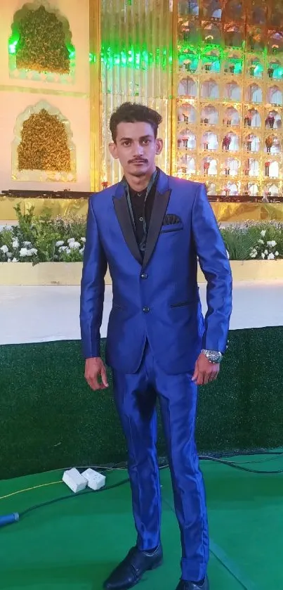 Man in a blue suit at a decorated event backdrop.