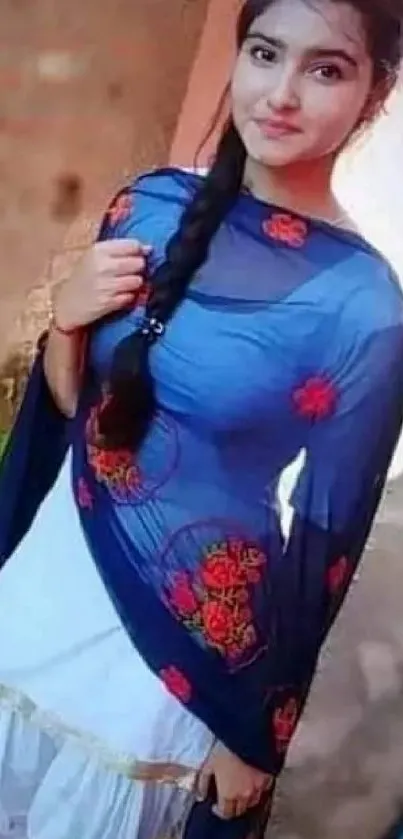 Elegant woman in blue shalwar kameez with red embroidery.