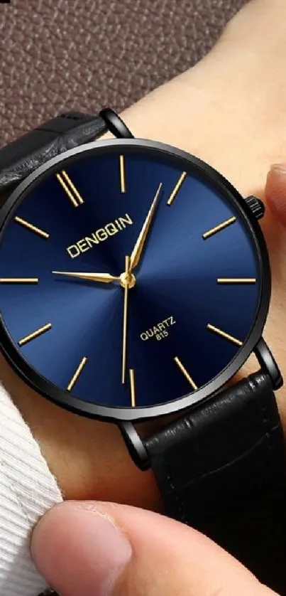 Elegant watch with a blue face on wrist.