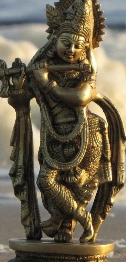 Brass Krishna statue on ocean shore in serene light.