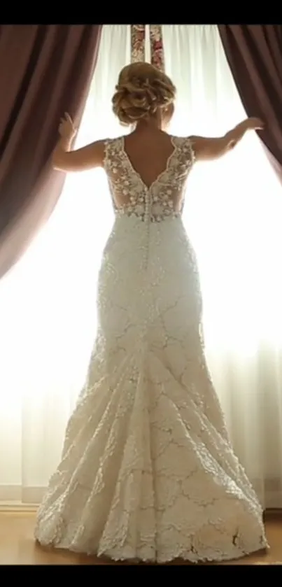 Bride in lace gown next to bright curtain.