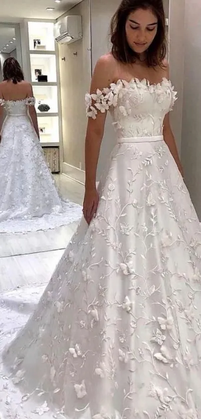 Woman in elegant white bridal gown with reflection, in fitting room.