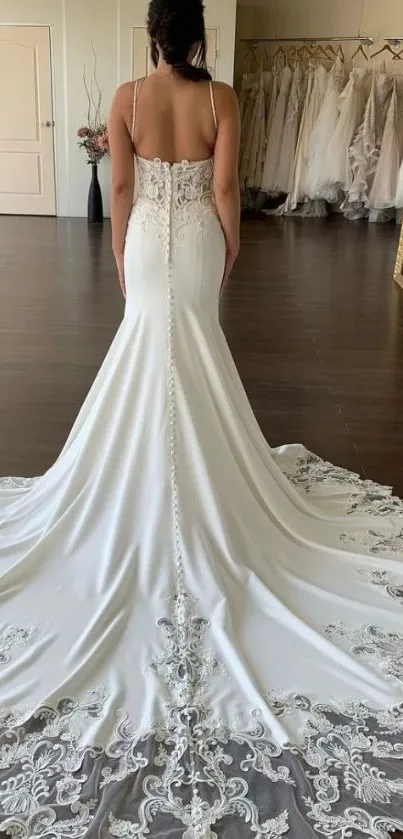 Stunning bridal gown with intricate lace and flowing train in a boutique setting.