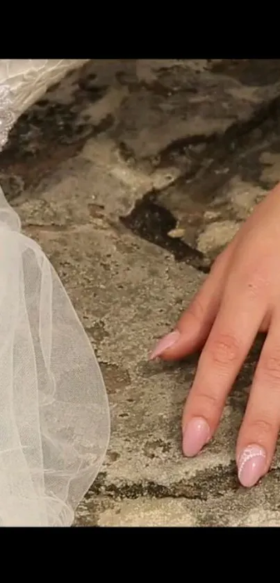 Elegant bridal hand on textured stone surface in vintage style.