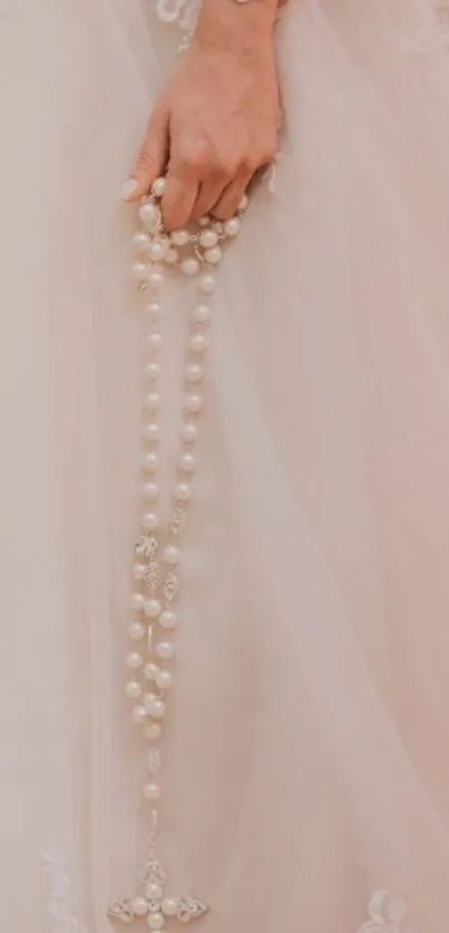 Bridal lace gown with pearl rosary in blush tones.