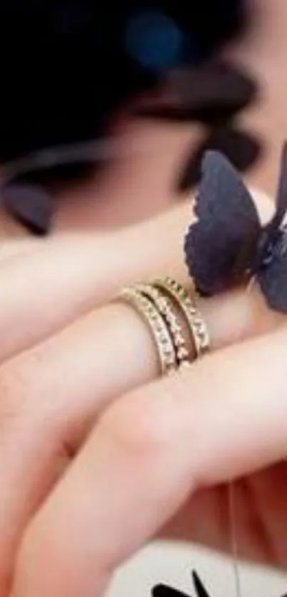 Hand with rings and black butterflies, elegant design.