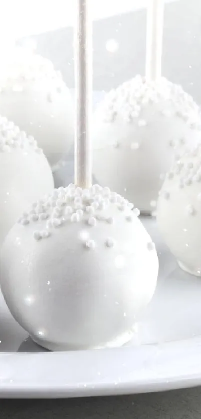 Elegant white cake pops arranged on a plate, minimalist dessert style.