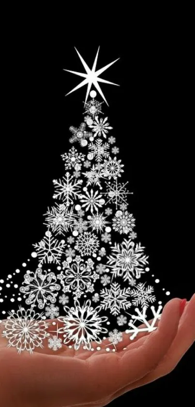 Hand holding snowflake Christmas tree on black background wallpaper.