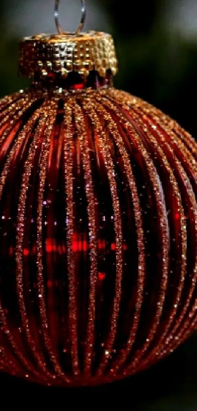 A red and gold Christmas bauble hanging from a tree, ideal for festive mobile backgrounds.