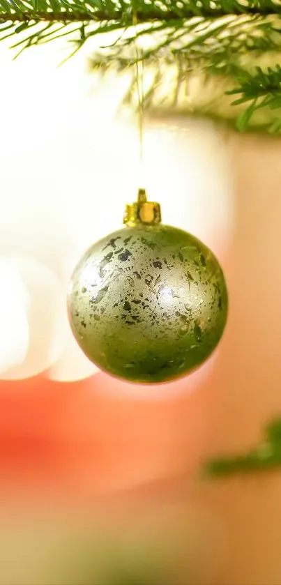 Green Christmas bauble hanging from a tree branch, festive wallpaper.