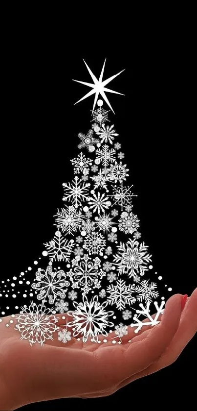 Hand holding an elegant silver Christmas tree on black background.