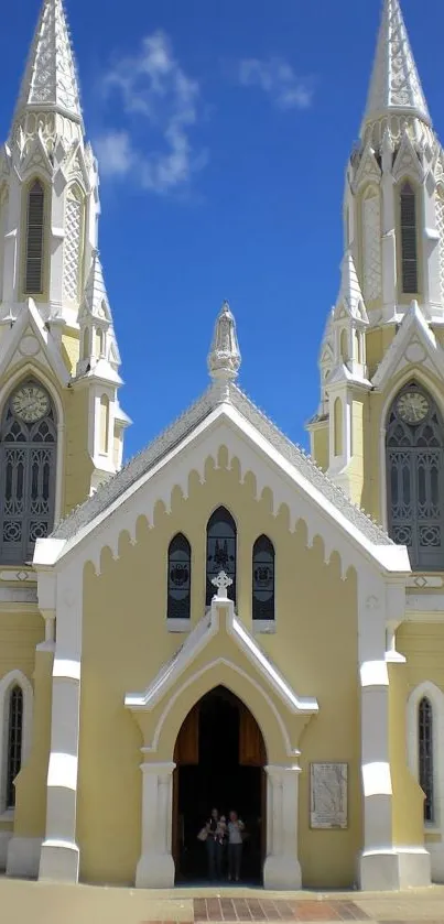 Elegant church facade with twin spires under a clear blue sky.