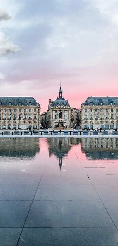 Cityscape with pink sunset reflected on water.