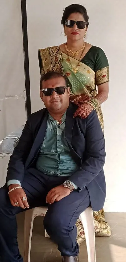 Elegant couple seated in sunglasses, full view.