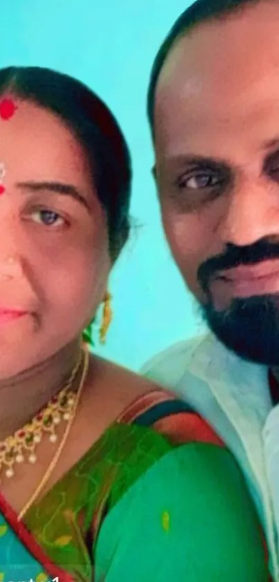 Vibrant couple portrait in traditional attire with a sky blue background.