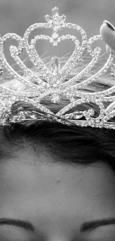 Black and white image of a crown being placed gracefully on a head.