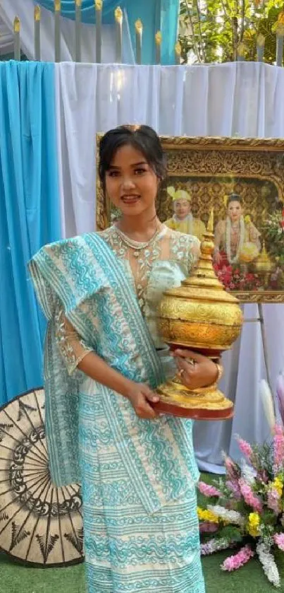 Person in traditional attire holding ceremonial object, with blue themed decor.
