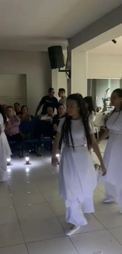 Cultural dance performance in a modern hall with dancers in white attire.