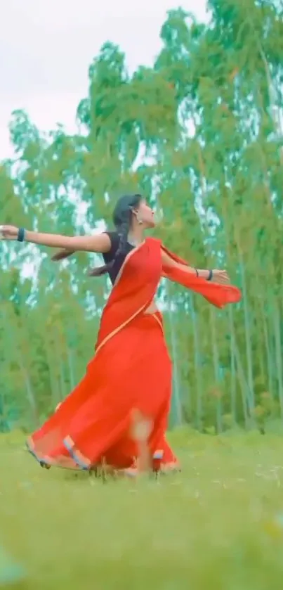 Woman in red saree dancing in a green field.