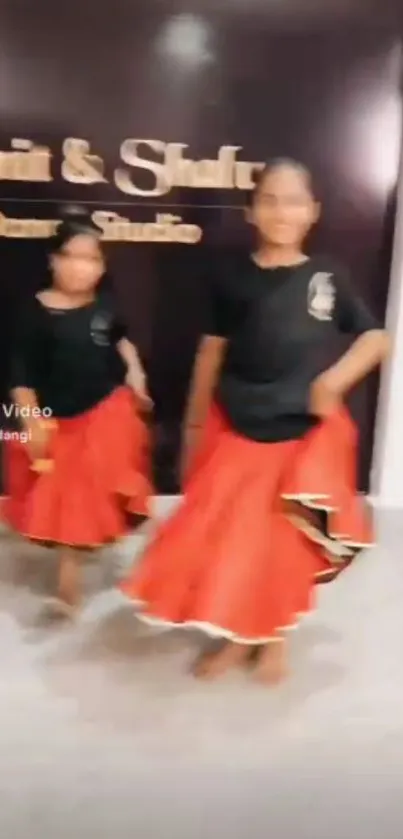 Elegant dancers in red skirts at a dance studio.