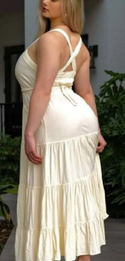 Woman in cream dress standing outdoors.