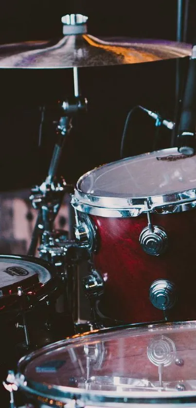 Close-up of a maroon drum set on stage with microphones.