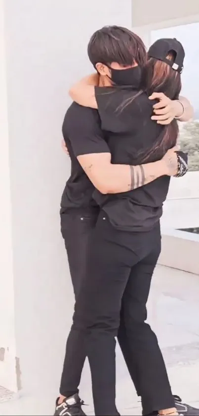 Elegant couple in black clothes embracing in sunlight.