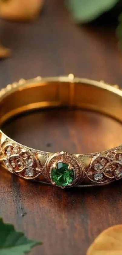 Elegant gold bracelet with emerald stones on a wooden surface.