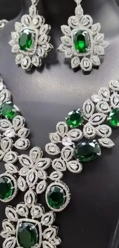 Elegant emerald and silver jewelry on display bust.
