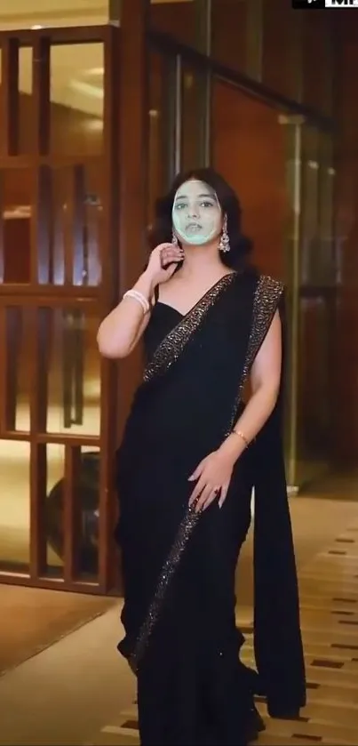 Elegant woman in a black saree posing indoors.