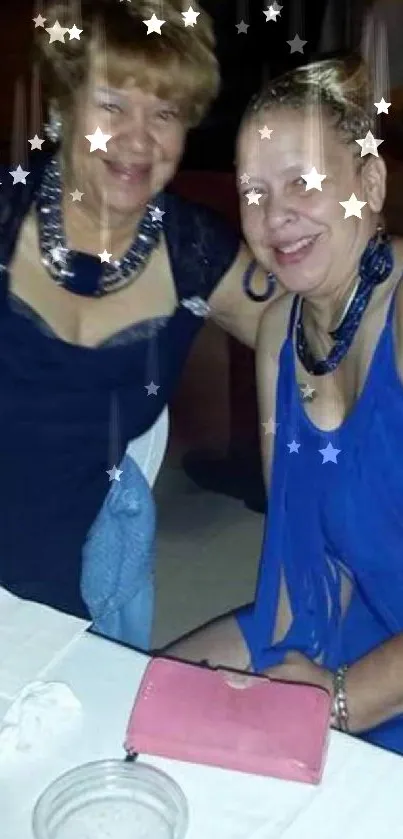 Two women in elegant blue attire at an evening gathering.