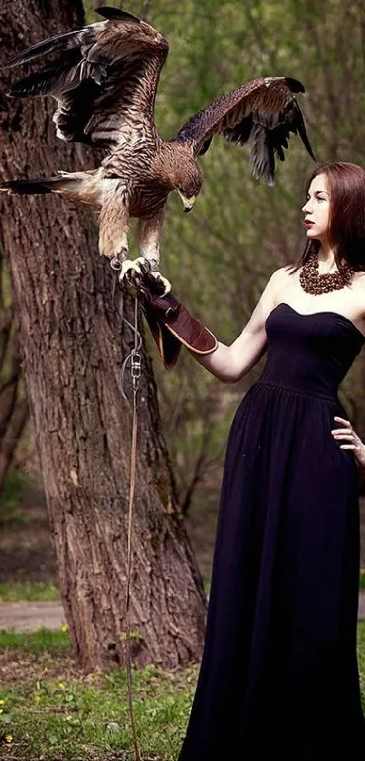 Woman in black dress with falcon in forest setting.