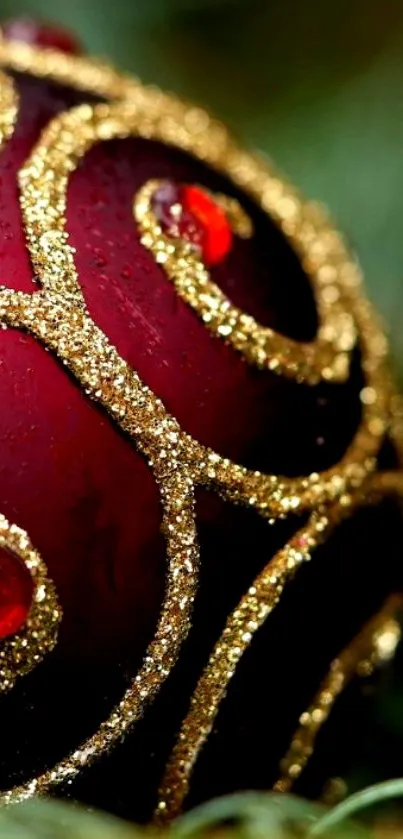 Close-up of a red ornament with gold glitter swirls.