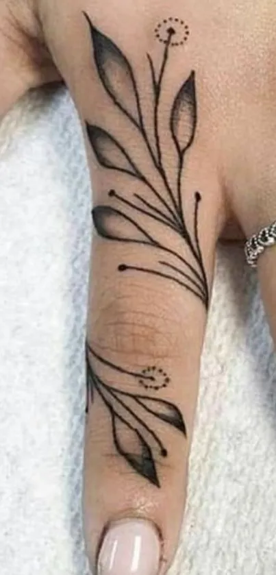 Elegant black ink leaf tattoo on finger with minimalist style.