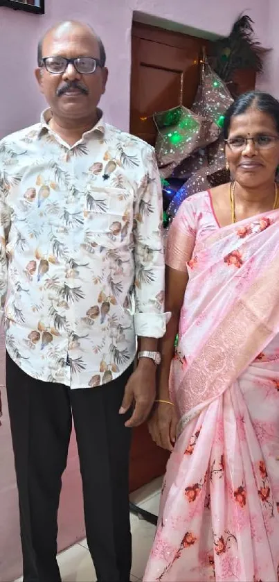 A man and woman in elegant floral attire standing indoors.