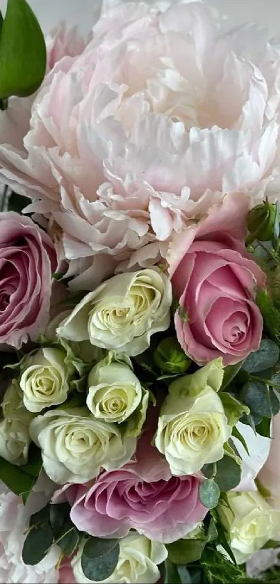 Elegant bouquet of pink and cream roses with lush green leaves.