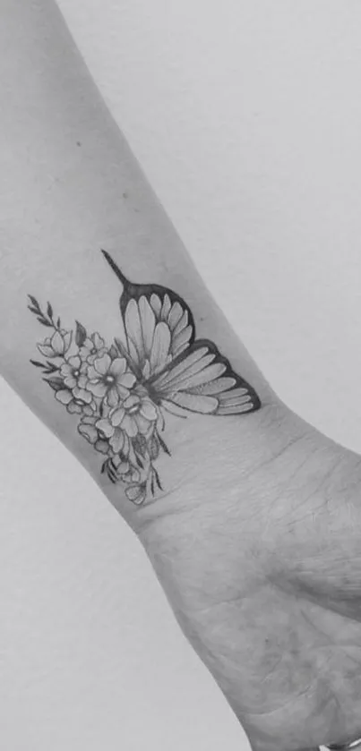 Elegant grayscale butterfly and floral tattoo design on the wrist.