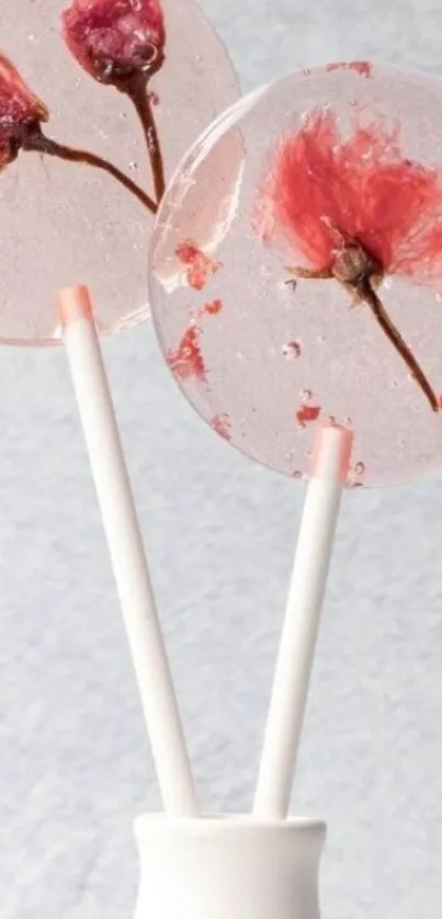 Two pink floral lollipops against a light gray background.